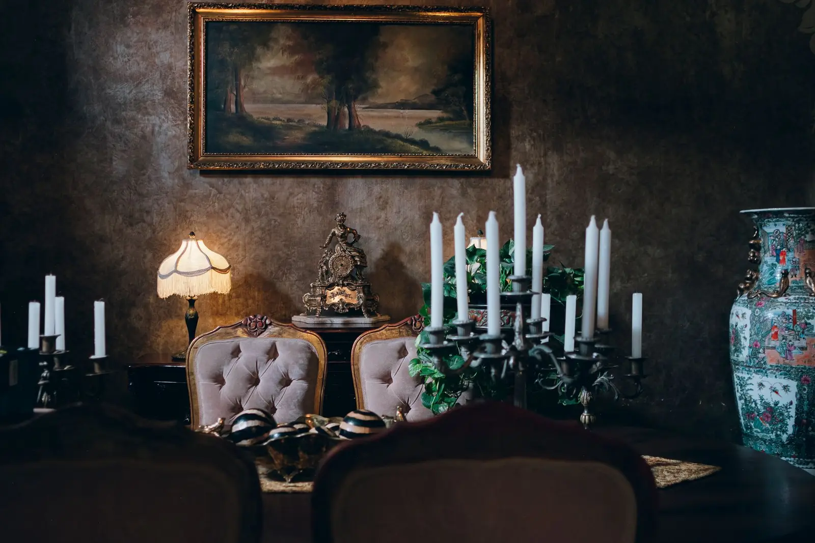 Donkere eetkamer met diepbruine wanden, kaarsen en een klassiek schilderij.